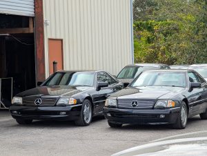 Mercedes R129 both in black parked outside Eurospec Autowerks.